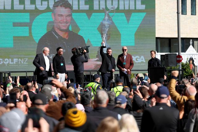 New Zealand golfer Ryan Fox (C) hold the the Open Championship Claret Jug trophy aloft at a public celebration in Auckland on July 28, 2026. Fox returned to New Zealand for a public celebration at Takutai Square in Auckland after winning the (British) Open Championship at the Royal Birkdale golf course in England on July 19. (Photo by Ben STRANG / AFP)