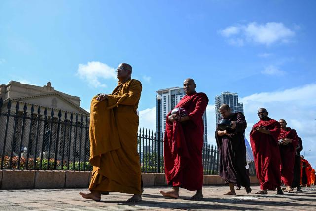 Sri Lankan Buddhist monks queue up for food along a road in Colombo on July 28, 2026. (Photo by Ishara S. KODIKARA / AFP)