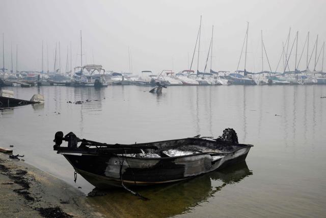 A charred boat is seen at the San Juan reservoir after a wildfire ravaged the region, in Pelayos de la Presa, 65 kilometres southwest of Madrid, on July 28, 2026. Firefighters in Spain made progress after a "positive night" against wildfires raging west of Madrid that have forced the evacuation of tens of thousands of people, Interior Minister Fernando Grande-Marlaska said today. Spain's government declared a national emergency last week over some of the worst wildfires in the country's history raging in fronts across the Madrid region, Avila province, Toledo and eastern Valencia. (Photo by Miguel RIOPA / AFP)