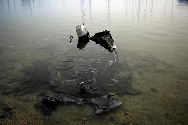 A melted boat is seen submerged in the San Juan reservoir after a wildfire ravaged the region, in Pelayos de la Presa, 65 kilometres southwest of Madrid, on July 28, 2026. Firefighters in Spain made progress after a "positive night" against wildfires raging west of Madrid that have forced the evacuation of tens of thousands of people, Interior Minister Fernando Grande-Marlaska said today. Spain's government declared a national emergency last week over some of the worst wildfires in the country's history raging in fronts across the Madrid region, Avila province, Toledo and eastern Valencia. (Photo by Miguel RIOPA / AFP)