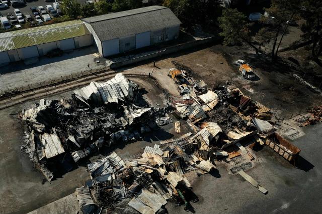 This aerial photograph shows burnt premisses and vehicles destroyed by a wildfire in a business park in Biscarrosse, southwestern France on July 28, 2026. The fire that broke out on July 23, 2026, near Biscarrosse in the Landes region of southwestern France has been "contained," France's President announced on July 27.
The Landes de Gascogne forest, home to maritime pines and a vital "lung" for the timber industry, has seen 42,000 hectares burn near Bordeaux. Forests are catching fire all the more easily because European vegetation and soils have been very dry for monthsa drought exacerbated by climate change and recent exceptional heatwaves. (Photo by Philippe Lopez / AFP)