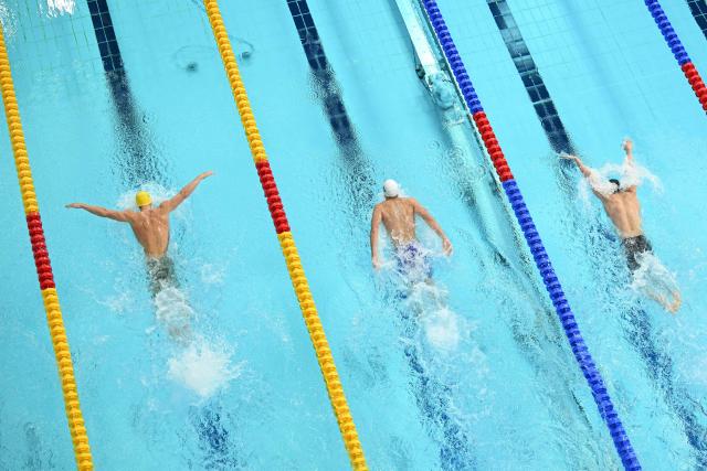 Australia's Brendon Smith (L), Namibia's Oliver Benjamin Durand (C) and Malaysia's Khai Xin Tan compete in the Men's 400m Individual Medley - Heats at the swimming event at the Tollcross International Swimming Centre in Glasgow, on day five of the Commonwealth Games in Glasgow, Scotland, on July 28, 2026. (Photo by Oli SCARFF / AFP)