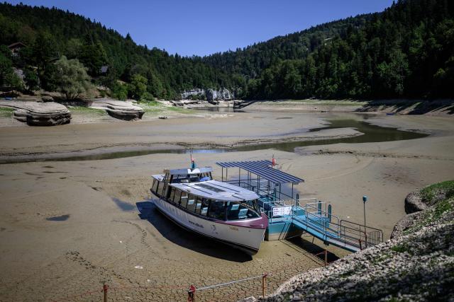 This photograph shows the parched bed of Brenets Lake (Lac des Brenets), part of the Doubs River, a natural border between eastern France and western Switzerland, as central Europe is in a third heatwave since June, in Les Brenets on July 28, 2026. The river has dried up due to a combination of factors, including geological fissures that drain water underground, below-average rainfall and repeated heatwaves. (Photo by Fabrice COFFRINI / AFP)
