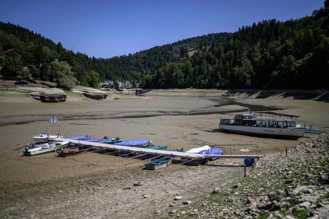 This photograph shows the parched bed of Brenets Lake (Lac des Brenets), part of the Doubs River, a natural border between eastern France and western Switzerland, as central Europe is in a third heatwave since June, in Les Brenets on July 28, 2026. The river has dried up due to a combination of factors, including geological fissures that drain water underground, below-average rainfall and repeated heatwaves. (Photo by Fabrice COFFRINI / AFP)
