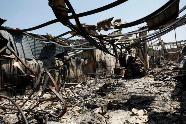 This picture shows a destroyed warehouse following a wildfire near La Adrada, 95 kilometres west of Madrid, on July 28, 2026. Spanish Prime Minister Pedro Sanchez said today that the country is starting to see the light at the "end of the tunnel in the fight against these wildfires," although he warned of "particularly complex hours" ahead as a new heatwave is set to hit the country starting tomorrow. The provinces of Avila, Madrid, Toledo, and Castellon continue to battle wildfires that have already burned over 77,000 hectares and forced the preventive evacuation of 63,000 people, according to figures from the Ministry of the Interior. (Photo by Oscar DEL POZO / AFP)
