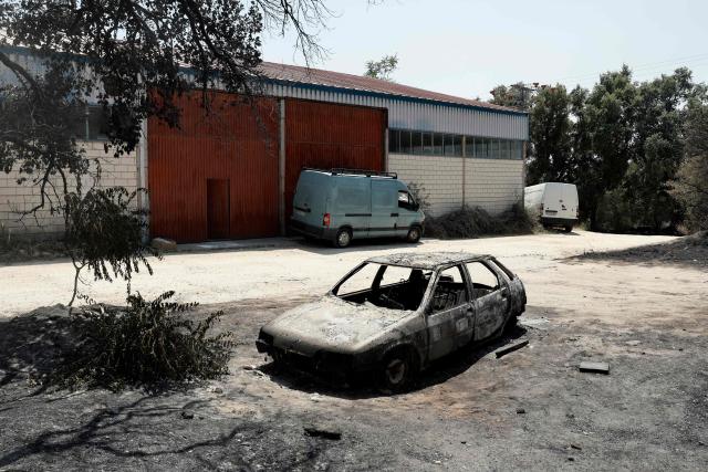 This picture shows a burnt-out car following a wildfire near La Adrada, 95 kilometres west of Madrid, on July 28, 2026. Spanish Prime Minister Pedro Sanchez said today that the country is starting to see the light at the "end of the tunnel in the fight against these wildfires," although he warned of "particularly complex hours" ahead as a new heatwave is set to hit the country starting tomorrow. The provinces of Avila, Madrid, Toledo, and Castellon continue to battle wildfires that have already burned over 77,000 hectares and forced the preventive evacuation of 63,000 people, according to figures from the Ministry of the Interior. (Photo by Oscar DEL POZO / AFP)