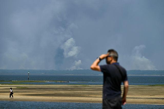 This photograph shows smoke from the wildfire on the west of Bordeux, seen from the Arcachon bay in Gujan-Mestras, southwestern France on July 28, 2026. The fire that broke out on July 23, 2026, near Biscarrosse in the Landes region of southwestern France has been "contained," France's President announced on July 27. The Landes de Gascogne forest, home to maritime pines and a vital "lung" for the timber industry, has seen 42,000 hectares burn near Bordeaux. Forests are catching fire all the more easily because European vegetation and soils have been very dry for monthsa drought exacerbated by climate change and recent exceptional heatwaves. (Photo by Philippe Lopez / AFP)