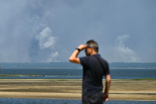 This photograph shows smoke from the wildfire on the west of Bordeux, seen from the Arcachon bay in Gujan-Mestras, southwestern France on July 28, 2026. The fire that broke out on July 23, 2026, near Biscarrosse in the Landes region of southwestern France has been "contained," France's President announced on July 27. The Landes de Gascogne forest, home to maritime pines and a vital "lung" for the timber industry, has seen 42,000 hectares burn near Bordeaux. Forests are catching fire all the more easily because European vegetation and soils have been very dry for monthsa drought exacerbated by climate change and recent exceptional heatwaves. (Photo by Philippe Lopez / AFP)