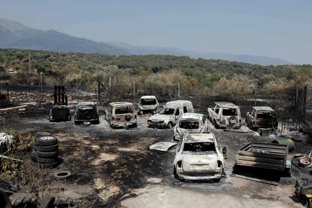 This picture shows charred cars following a wildfire in Casavieja, 100 kilometers south-west of Madrid, on July 28, 2026. Spanish Prime Minister Pedro Sanchez said today that the country is starting to see the light at the "end of the tunnel in the fight against these wildfires," although he warned of "particularly complex hours" ahead as a new heatwave is set to hit the country starting tomorrow. The provinces of Avila, Madrid, Toledo, and Castellon continue to battle wildfires that have already burned over 77,000 hectares and forced the preventive evacuation of 63,000 people, according to figures from the Ministry of the Interior. (Photo by Oscar DEL POZO / AFP)