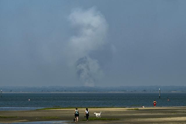 This photograph shows smoke from the wildfire on the west of Bordeux, seen from the Arcachon bay in Gujan-Mestras, southwestern France on July 28, 2026. The fire that broke out on July 23, 2026, near Biscarrosse in the Landes region of southwestern France has been "contained," France's President announced on July 27. The Landes de Gascogne forest, home to maritime pines and a vital "lung" for the timber industry, has seen 42,000 hectares burn near Bordeaux. Forests are catching fire all the more easily because European vegetation and soils have been very dry for monthsa drought exacerbated by climate change and recent exceptional heatwaves. (Photo by Philippe Lopez / AFP)