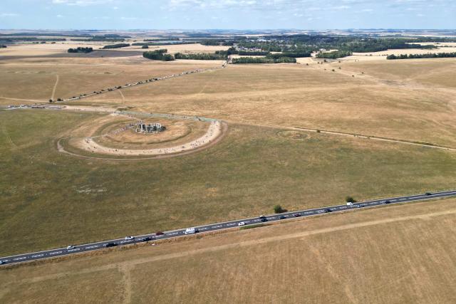 This aerial image shows the scorched grass surrounding the area at Stonehenge near Amesbury, Wiltshire in southern England on July 28, 2026. Temperatures were forecast this week to rise back into the 30s for parts of England, following three heatwaves so far over the summer. (Photo by JUSTIN TALLIS / AFP)