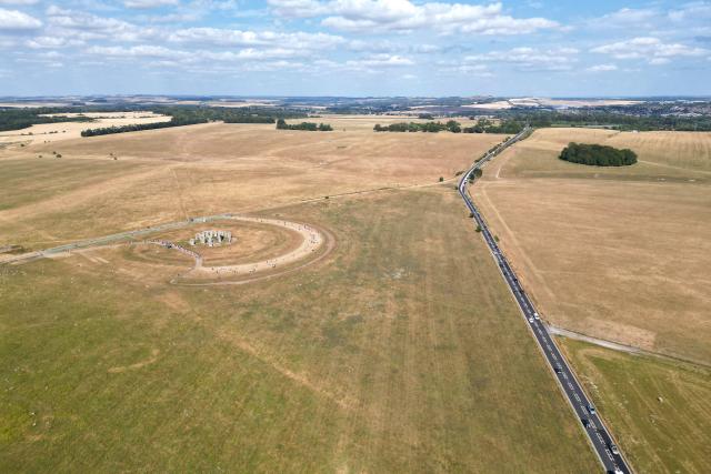This aerial image shows the scorched grass surrounding the area at Stonehenge near Amesbury, Wiltshire in southern England on July 28, 2026. Temperatures were forecast this week to rise back into the 30s for parts of England, following three heatwaves so far over the summer. (Photo by JUSTIN TALLIS / AFP)