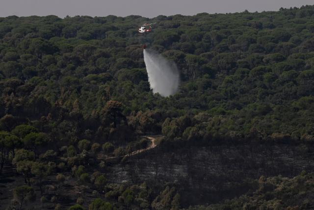A firefighting helicopter drops water to refresh a burnt area affected by wildfires near San Martin de Valdeiglesias, some 70 kilometres west of Madrid, Spain on July 28, 2026. Spain's Prime Minister Pedro Sanchez said on July 28, 2026, firefighters were starting to see "light at the end of the tunnel" in their battle against some of the worst forest fires in the country's history. (Photo by MIGUEL RIOPA / AFP)