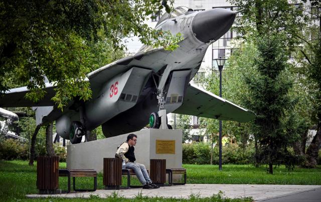 A man sits next to Soviet MiG-29 jet fighter installed in a park in Moscow on July 29, 2026. The Mikoyan MiG-29 jet fighter was developed in the the 1970s, and usage started in the Soviet Air Forces in 1983. (Photo by Alexander NEMENOV / AFP)