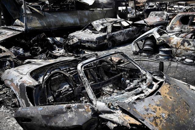 Burnt-out vehicles are seen in an industrial estate ravaged by a wildfire in Chapineria, 50 kilometres west of Madrid, on July 29, 2026. Spain's Prime Minister Pedro Sanchez said today that the coming hours would be "decisive" to extinguish a major wildfire near Madrid as more of the tens of thousands of evacuees were authorised to return home, following the returns in previous days. Emergency services have been working since last week to put out the blaze in the Madrid region, and another in the nearby province of Avila which officials said is the worst in Spain's recent history. The wildfires have burned nearly 80,000 hectares (200,000 acres) overall, according to authorities (Photo by Miguel RIOPA / AFP)