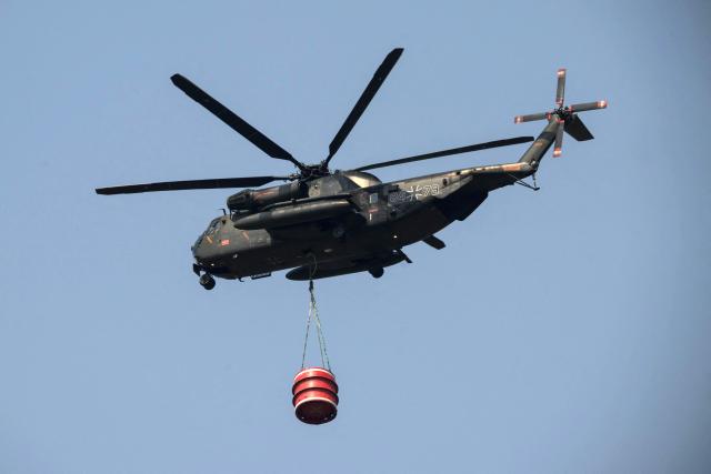 German military personnel aboard a German CH-53 helicopter assist with fire fighting in Lanton, east of the Arcachon Bay, west of Bordeaux on July 29, 2026, during wildfires in the Gironde region, southwestern France. National weather office MeteoFrance forecast a rise in temperatures inland up to 35C later on July 28, 2026, with ocean winds from the west that could fan the flames. July 29 was expected to bring temperatures of 40C, with lighter, dry winds. Scientists have long warned that climate change caused by human use of fossil fuels will make periods of drought more intense and longer-lasting, creating the ideal conditions for wildfires. (Photo by Ed JONES / AFP)