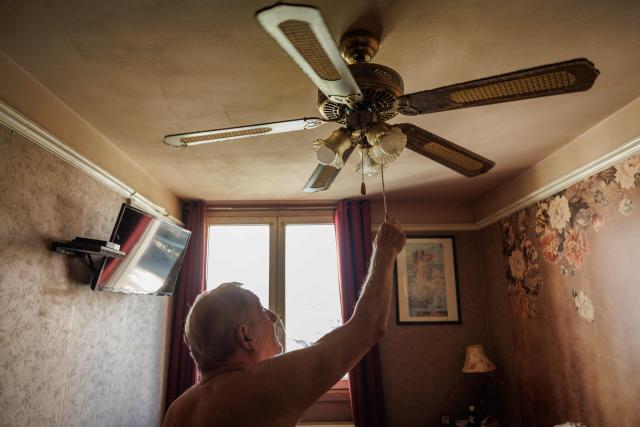 Daniel Molignier, 80, turns on the ceiling fan in his apartment at Place des Fêtes during a hot summer day in Paris on July 29, 2026. The retired couple say their home turns into a "thermal kettle" during heatwaves, becoming unbearably hot. Western Europe this year experienced its hottest June on record as a searing heatwave swept across a continent facing increasingly frequent and intense heat extremes, the EU's climate monitor said on July 9, 2026. (Photo by Simon WOHLFAHRT / AFP)