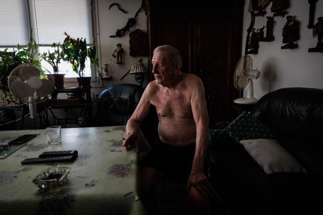 Daniel Molignier, 80, smokes a cigar next to fans in his apartment at Place des Fêtes during a hot summer day in Paris on July 29, 2026. The retired couple say their home turns into a "thermal kettle" during heatwaves, becoming unbearably hot. Western Europe this year experienced its hottest June on record as a searing heatwave swept across a continent facing increasingly frequent and intense heat extremes, the EU's climate monitor said on July 9, 2026. (Photo by Simon WOHLFAHRT / AFP)