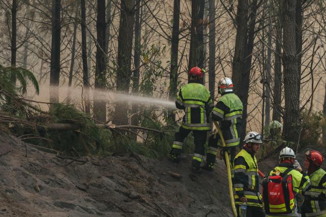 Firefighters use a hose to spray water amid operations against a wildfire near Lanton, southwestern France, on July 29, 2026. The return of intense heat on July 29, 2026, and sea winds are fanning the megafire in Gironde, with new flare-ups in places after a second, calmer night that had made it possible to “stabilize” the blaze. Forests catch fire all the more easily because the vegetation and soil have been extremely dry for months, a drought worsened by climate change and the recent exceptional heatwaves. (Photo by Alain JOCARD / AFP)
