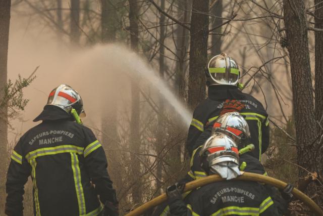 Firefighters use a hose to spray water amid operations against a wildfire near Lanton, southwestern France, on July 29, 2026. The return of intense heat on July 29, 2026, and sea winds are fanning the megafire in Gironde, with new flare-ups in places after a second, calmer night that had made it possible to “stabilize” the blaze. Forests catch fire all the more easily because the vegetation and soil have been extremely dry for months, a drought worsened by climate change and the recent exceptional heatwaves. (Photo by Alain JOCARD / AFP)