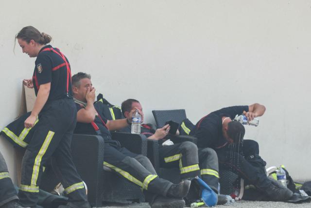 Firefighters rest with water bottles during a break amid operations against a wildfire near Lanton, southwestern France, on July 29, 2026. The return of intense heat on July 29, 2026, and sea winds are fanning the megafire in Gironde, with new flare-ups in places after a second, calmer night that had made it possible to “stabilize” the blaze. Forests catch fire all the more easily because the vegetation and soil have been extremely dry for months, a drought worsened by climate change and the recent exceptional heatwaves. (Photo by Alain JOCARD / AFP)
