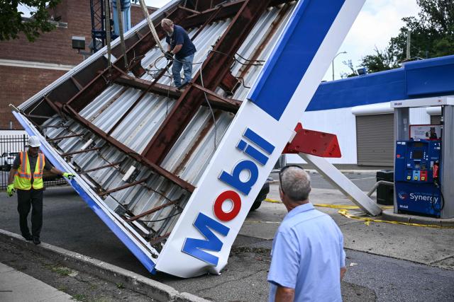 Workers inspect a collapsed canopy of a Mobil gas station a day after severe storms swept through Washington, DC, on July 29, 2026. (Photo by Brendan SMIALOWSKI / AFP)