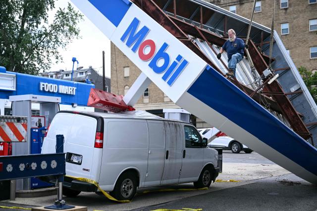 Workers inspect a collapsed canopy of a Mobil gas station a day after severe storms swept through Washington, DC, on July 29, 2026. (Photo by Brendan SMIALOWSKI / AFP)