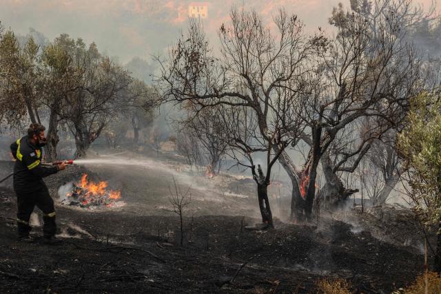 A fireman sprays water to extinguish a fire in the town of Plomari on the Greek island of Lesbos on July 29, 2026. (Photo by Manolis Lagoutaris / AFP)