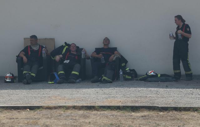 Firefighters rest with water bottles amid operations against a wildfire near Lanton, southwestern France, on July 29, 2026. The return of intense heat on July 29, 2026, and sea winds are fanning the megafire in Gironde, with new flare-ups in places after a second, calmer night that had made it possible to “stabilize” the blaze. Forests catch fire all the more easily because the vegetation and soil have been extremely dry for months, a drought worsened by climate change and the recent exceptional heatwaves. (Photo by Alain JOCARD / AFP)