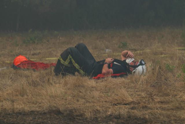 A firefighter rests on the dried out grass amid operations against a wildfire near Lanton, southwestern France, on July 29, 2026. The return of intense heat on July 29, 2026, and sea winds are fanning the megafire in Gironde, with new flare-ups in places after a second, calmer night that had made it possible to “stabilize” the blaze. Forests catch fire all the more easily because the vegetation and soil have been extremely dry for months, a drought worsened by climate change and the recent exceptional heatwaves. (Photo by Alain JOCARD / AFP)