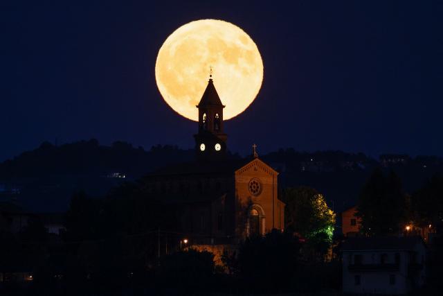 The "Elk Moon" rises behind the San Sebastiano church in the village of Serralunga d'Alba, Langhe Countryside, Northwestern Italy, on July 29, 2026. (Photo by Marco Bertorello / AFP)