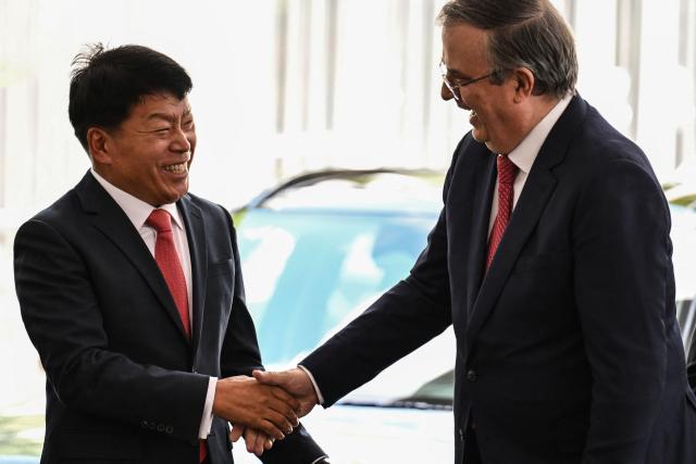 Andy Kim (L), President of South Korean automaker Kia in Mexico, and Mexican Economy Secretary Marcelo Ebrard shake hands during the presentation of the Kia EV3 electric vehicle in Mexico City on July 29, 2026. Mexico announced on July 29 a multi-million-dollar investment by South Korean automaker Kia, amid tariff pressure maintained by the administration of US President Donald Trump on the sector and the threat of new levies. (Photo by Yuri CORTEZ / AFP)