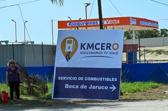 A woman stands next to a gas station under construction in Boca de Jaruco, Matabeque Province, Cuba on July 29, 2026. Cuba on July 29, 2026, moved to open several key crisis-ravaged sectors of its state-run economy to private firms, as the communist government tries to ease acute shortages resulting from a US energy blockade. (Photo by YAMIL LAGE / AFP)