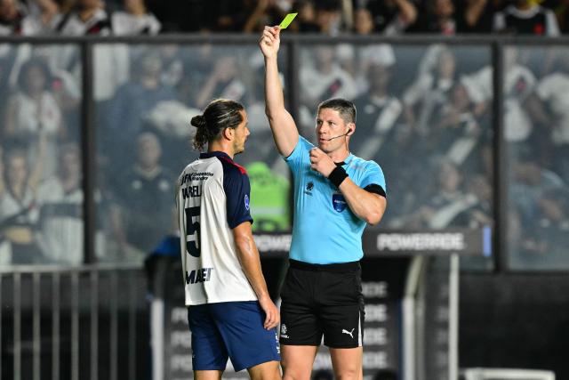 Argentine referee Maximiliano Ramirez shows a yellow card to Independiente Medellin's Uruguayan defender #05 Joaquin Varela during the second leg of the Copa Sudamericana knockout round play-off football match between Brazil's Vasco da Gama and Colombia's Independiente Medellin at the Sao Januario stadium, in Rio de Janeiro, Brazil, on July 29, 2026. (Photo by Pablo PORCIUNCULA / AFP)