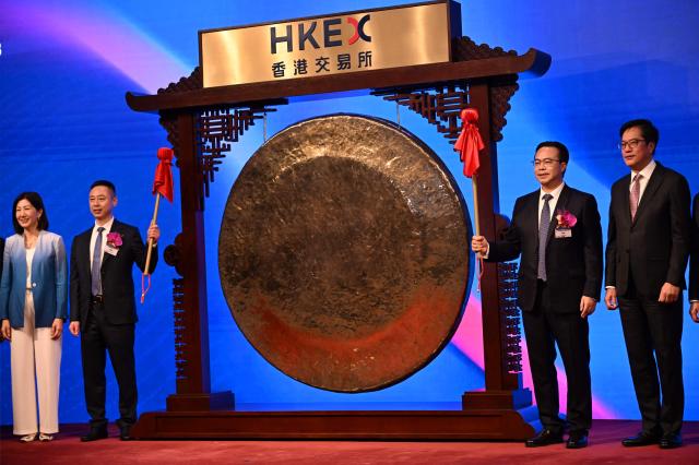 Liu Sheng, Chairman and CEO of Zhongji Innolight (centre R) poses after banging the gong at the start of trading with his director Wang Xiaodong (centre L) during the launch of the company's initial public offering (IPO) at the Hong Kong Exchanges and Clearing Limited (HKEX) in Hong Kong on July 30, 2026. (Photo by Peter PARKS / AFP)