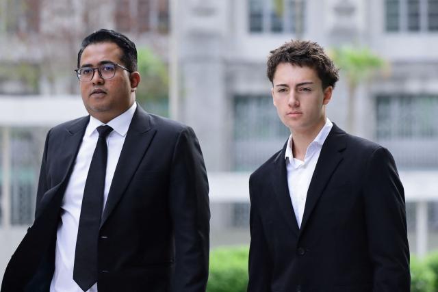 French teenager Didier Gaspard Owen Maximilien (R) and his lawyer arrive at the State Courts in Singapore on July 30, 2026. A French teenager pleaded guilty to a public nuisance charge in Singapore on July 30, for a straw-licking stunt that landed him in hot water in the city-state. (Photo by Suhaimi Abdullah / AFP)