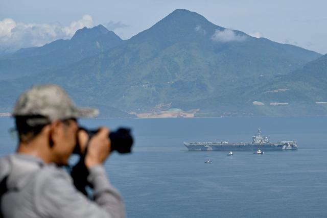 The man taking a photo of the USS George Washington arriving at the port in Danang on July 30, 2026. (Photo by Nhac NGUYEN / AFP)
