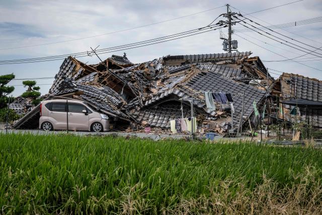A house is seen collapsed onto a car in Hikawa, Kumamoto Prefecture on July 30, 2026 after an earthquake struck the area. The Aeon shopping mall in Kumamoto had only reopened in June, gleaming, stronger and safer thanks to the latest renovations following earthquakes in 2016, promising a place where generations could "share smiles". But despite extensive reinforcement works on the facility that suffered severe damage a decade ago, a blast triggered by a fresh quake on July 28, in the southwestern Japanese region has left it in ruins. (Photo by Yuichi YAMAZAKI / AFP)