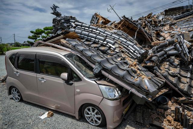 A house is seen collapsed onto a car in Hikawa, Kumamoto Prefecture on July 30, 2026 after an earthquake struck the area. The Aeon shopping mall in Kumamoto had only reopened in June, gleaming, stronger and safer thanks to the latest renovations following earthquakes in 2016, promising a place where generations could "share smiles". But despite extensive reinforcement works on the facility that suffered severe damage a decade ago, a blast triggered by a fresh quake on July 28, in the southwestern Japanese region has left it in ruins. (Photo by Yuichi YAMAZAKI / AFP)
