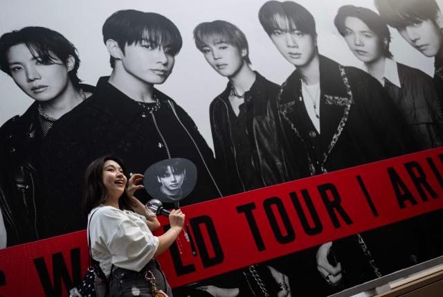 (FILES) A fan of Korean boy band BTS poses for a photo in front of a poster at Tokyo Dome before the start of the first BTS World Tour ‘Arirang’ in Tokyo on April 17, 2026. Global K-pop sensation BTS said on July 29, 2026, they will not submit their music for next year's Grammy Awards, after the Recording Academy introduced a new Asian pop category criticised for restricting the success of regional artists. (Photo by Andrew CABALLERO-REYNOLDS / AFP)