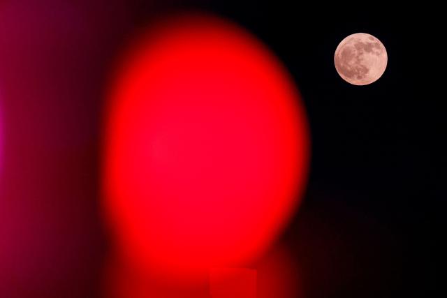 TOPSHOT - The "buck" full moon rises by decorative light installations in Doha on July 29, 2026. (Photo by KARIM JAAFAR / AFP)