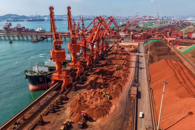 A cargo ship unloads imported iron ore at a port in Qingdao, in China’s eastern Shandong province on July 30, 2026. (Photo by CN-STR / AFP) / China OUT