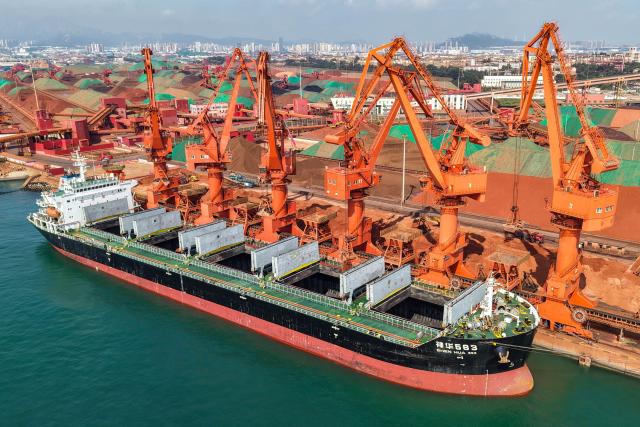 A cargo ship unloads imported iron ore at a port in Qingdao, in China’s eastern Shandong province on July 30, 2026. (Photo by CN-STR / AFP) / China OUT