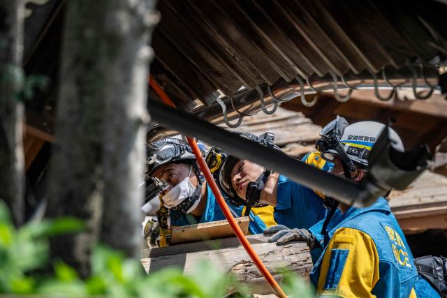 Rescue officials work at the site of a house that collapsed following the 28 July earthquake in Yatsushiro, Kumamoto prefecture on 30 July 2026. (Photo by Yuichi YAMAZAKI / AFP)