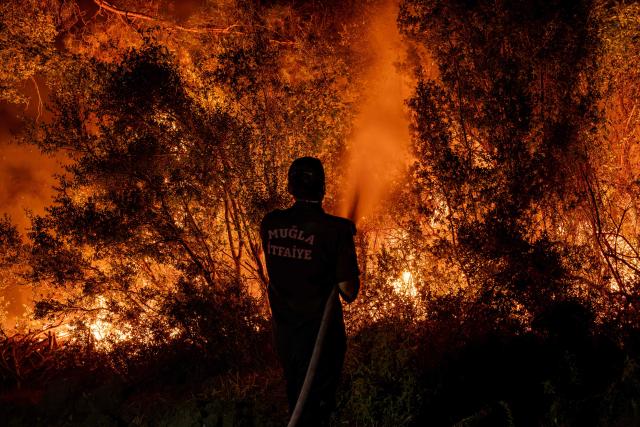 A firefighter uses a waterhose as they operate to battle a wildfire at Seydikemer district in Mugla on July 29, 2026. Turkish firefighters on July 29, 2026, battled wildfires near the country's southern tourist beaches that have forced the evacuation of hundreds of people, authorities said. Hundreds of firefighters went up against the biggest fire in Mugla province, with more than 20 planes and helicopters bombing water on the flames, the agriculture ministry said. (Photo by Murat Kocabas / AFP)
