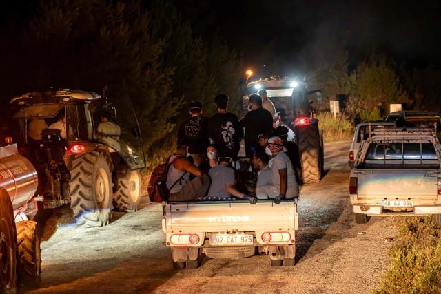 Firefighters and volunteers ride at the back of a pick-up truck as they battle a wildfire at Seydikemer district in Mugla on July 29, 2026. Turkish firefighters on July 29, 2026, battled wildfires near the country's southern tourist beaches that have forced the evacuation of hundreds of people, authorities said. Hundreds of firefighters went up against the biggest fire in Mugla province, with more than 20 planes and helicopters bombing water on the flames, the agriculture ministry said. (Photo by Murat Kocabas / AFP)