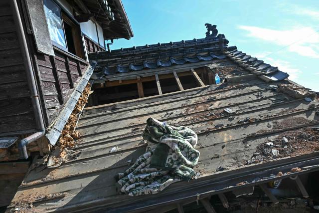 A blanket and bottle of water are seen on a destroyed house in Hikawa, Kumamoto Prefecture on July 30, 2026, after an earthquake struck southwestern Japan on July 28. (Photo by Philip FONG / AFP)