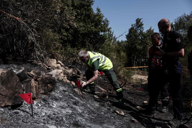 Members of the Recherche des Causes et Circonstances d'Incendie - RCCI of the Var department (Fire Causes and Circumstances Investigation) unit place red marker flags as they operate at the site of a suspected reignition point of a wildfire in Ponteves, south-eastern France on July 29, 2026. The RCCI comprises criminal investigation technicians from the French Gendarmerie, wildfire specialists from the fire service, and members of the National Forestry Office (ONF). Its role is to determine the cause of wildfires, including whether they were started deliberately or by natural causes. More than 600 people were evacuated on July 29, 2026, after a new fire broke out in the Var, south-east of Brignoles, spreading across about 100 hectares less than 24 hours after the Gros Bessillon wildfire, which burned 4,500 hectares over eight days, was brought under control. (Photo by Thibaud MORITZ / AFP)