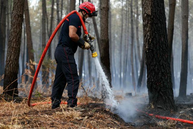 A firefighter uses a water hose as he works to extinguishing remaining hot spots and  smoldering patches in Lanton, west of Bordeaux on July 30, 2026, as a wildfire has been ravaging the forest north of the Arcachon Basin (Gironde) since July 22. After eight gruelling days battling a massive wildfire that has ravaged 42,000 hectares in Gironde (south-west France), the firefighters can see the light at the end of the tunnel, but the flare-ups observed in recent days are keeping the emergency services on tenterhooks. (Photo by Alain JOCARD / AFP)