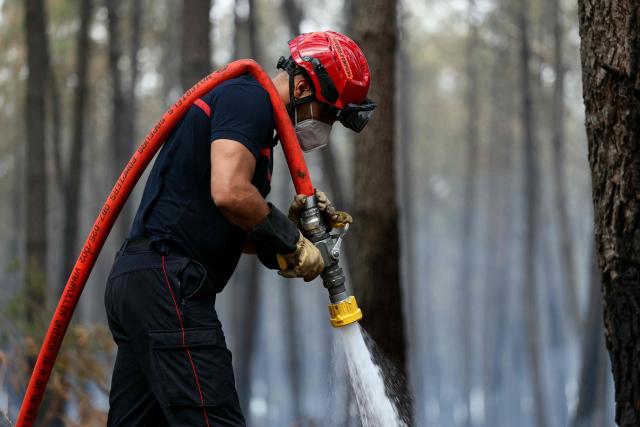 A firefighter uses a water hose as he works to extinguishing remaining hot spots and  smoldering patches in Lanton, west of Bordeaux on July 30, 2026, as a wildfire has been ravaging the forest north of the Arcachon Basin (Gironde) since July 22. After eight gruelling days battling a massive wildfire that has ravaged 42,000 hectares in Gironde (south-west France), the firefighters can see the light at the end of the tunnel, but the flare-ups observed in recent days are keeping the emergency services on tenterhooks. (Photo by Alain JOCARD / AFP)